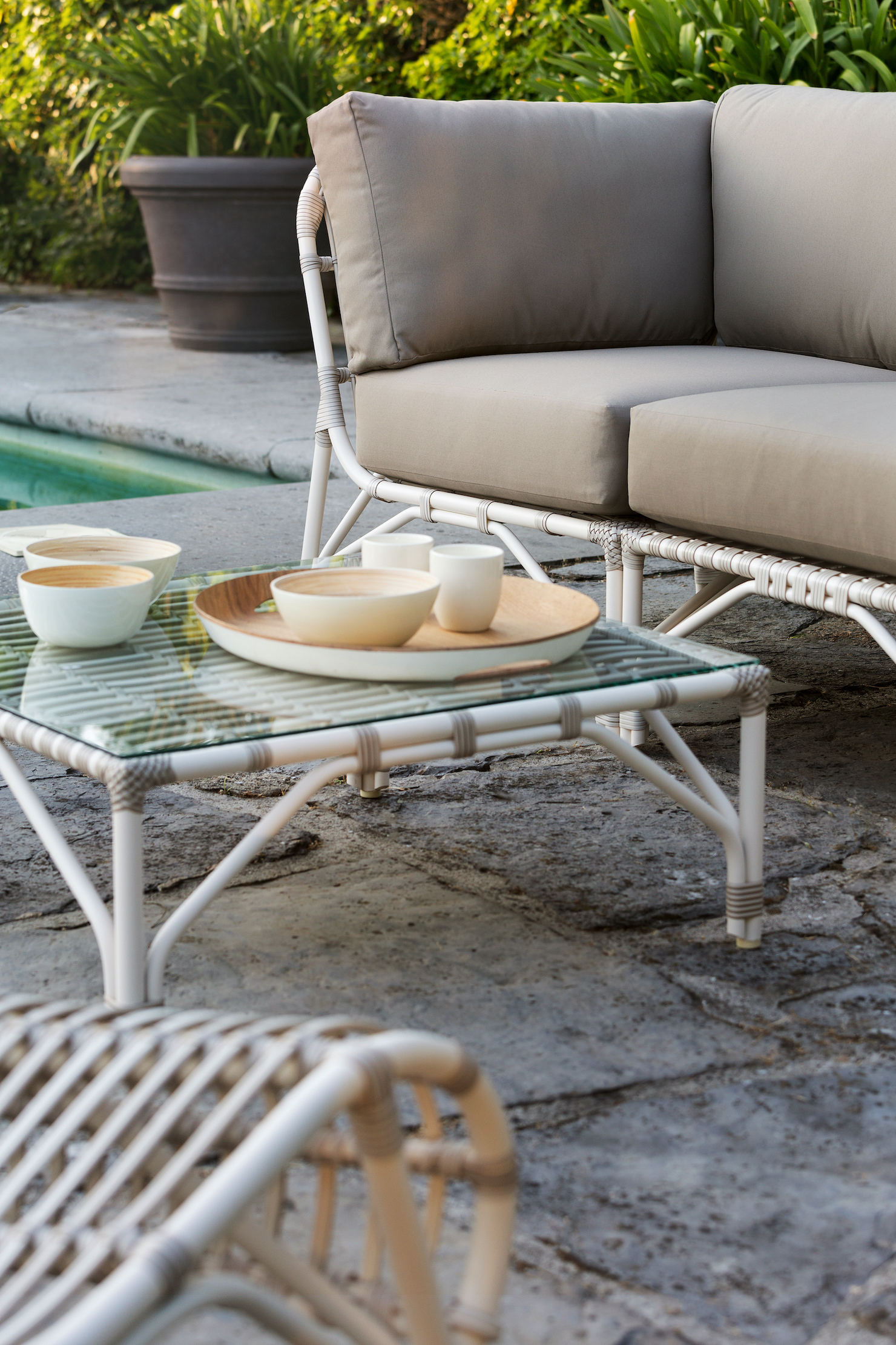 Vincent Sheppard Outdoor Tische und Sofa bei einem Pool mit Dekoration und Essen